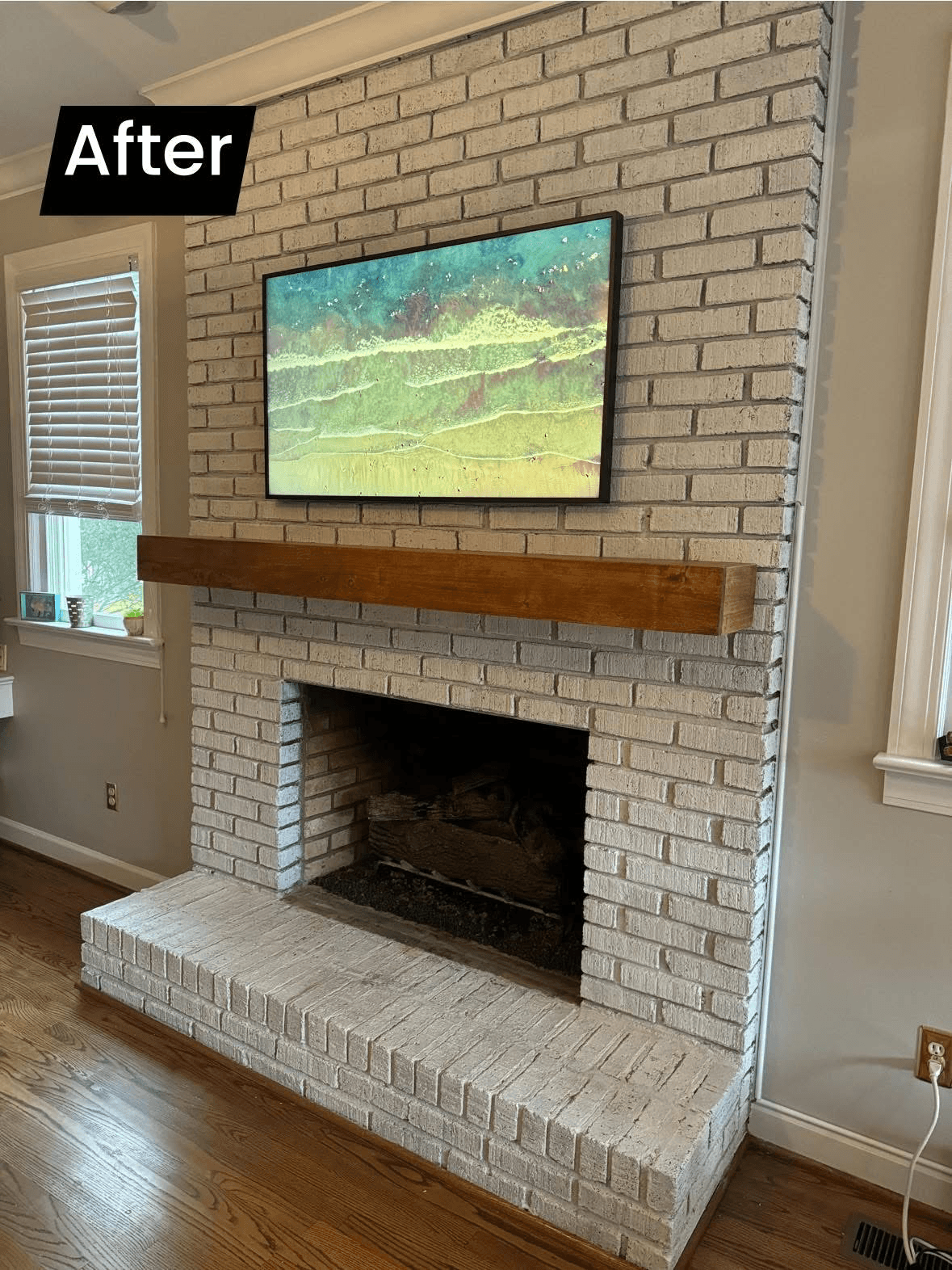 TV mounted above painted brick fireplace with wood mantle