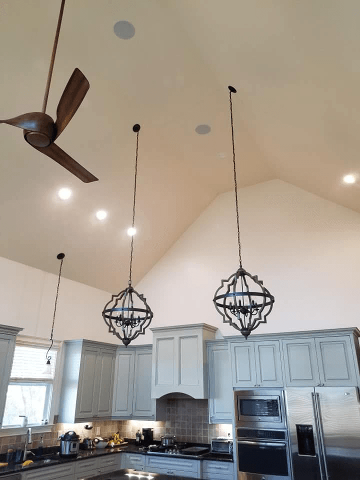 Vaulted kitchen ceiling with in-ceiling speakers and pendant chandeliers