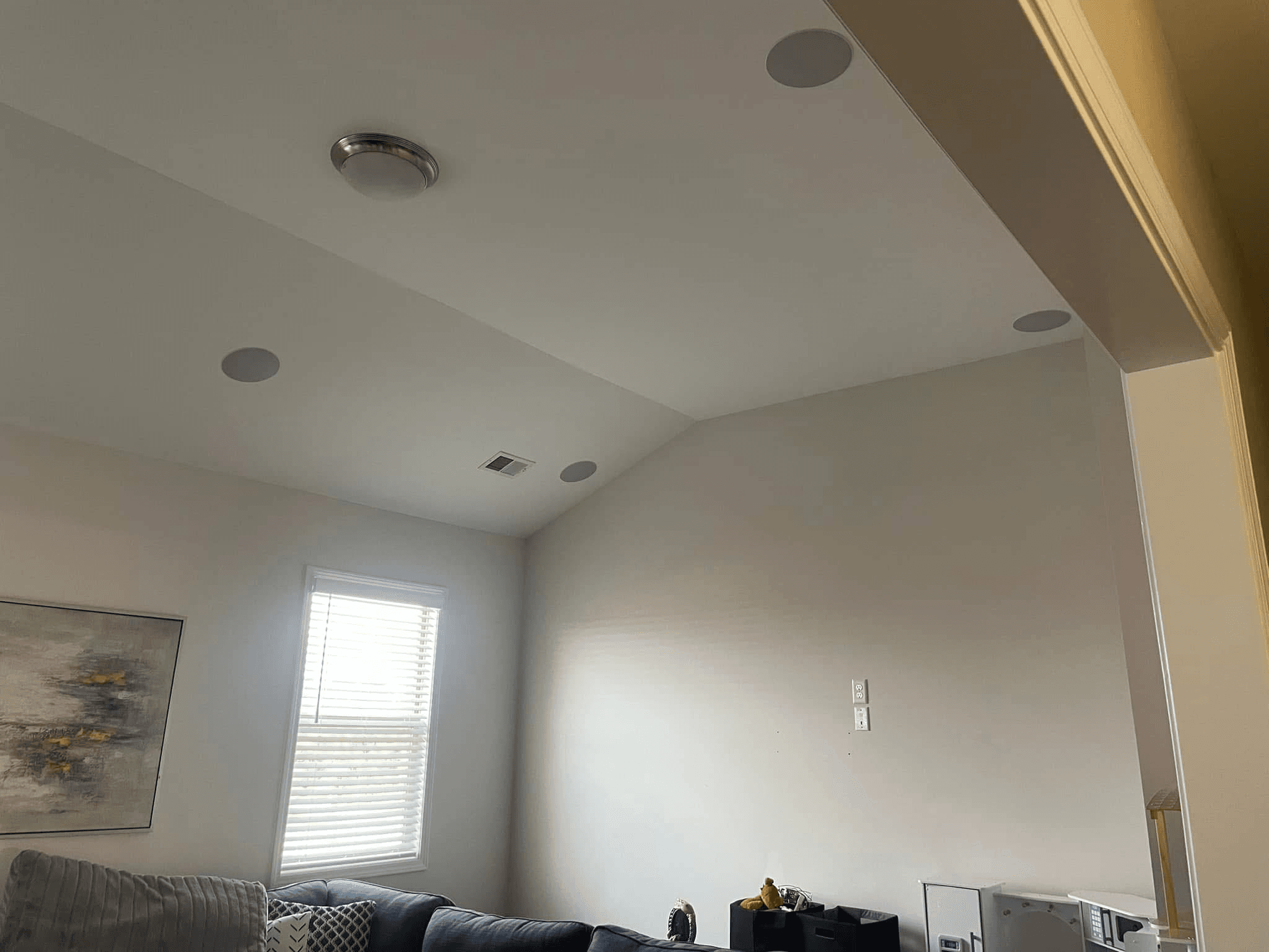 In-ceiling surround sound speakers installed in vaulted living room ceiling