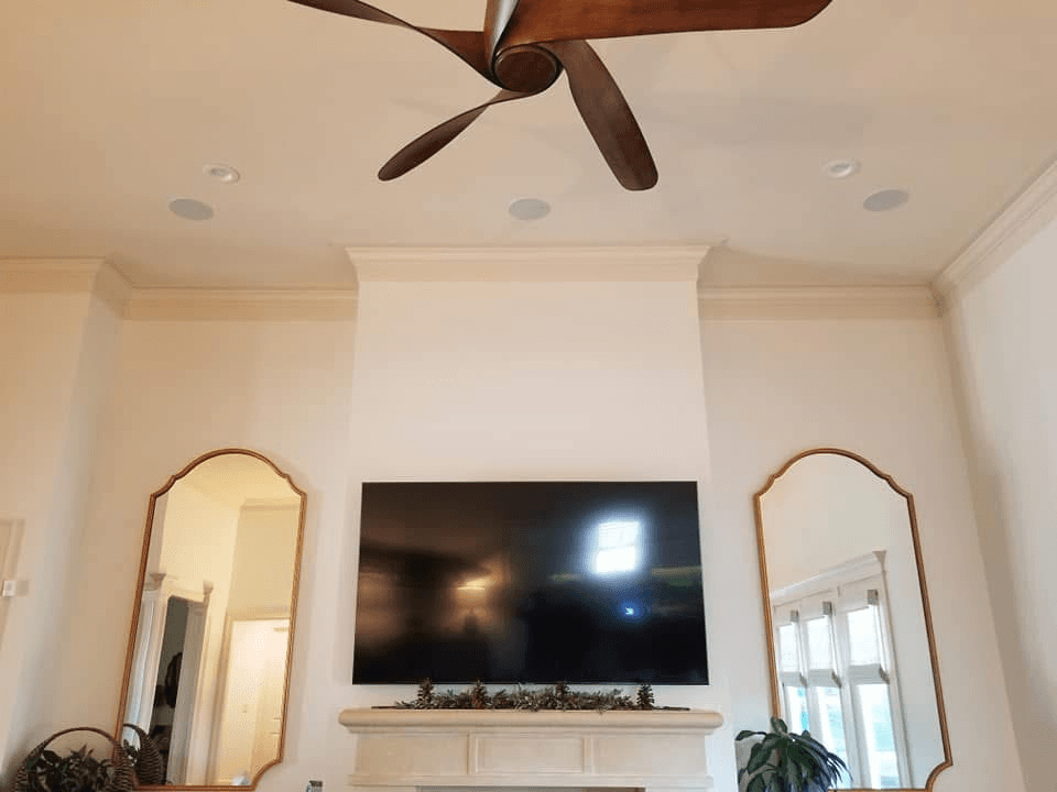 TV on corner stand with in-ceiling speakers in vaulted room with arched mirrors