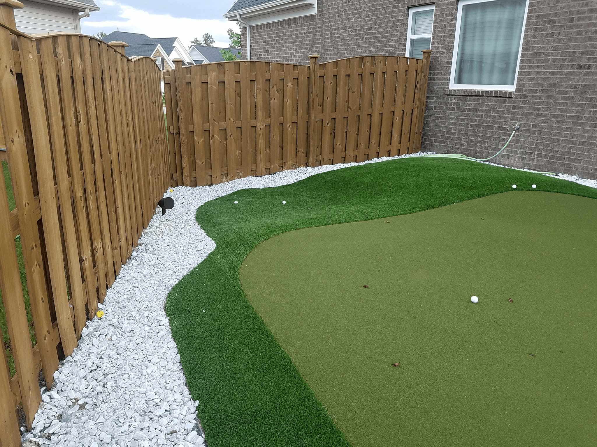 Backyard putting green with landscape audio speaker installation