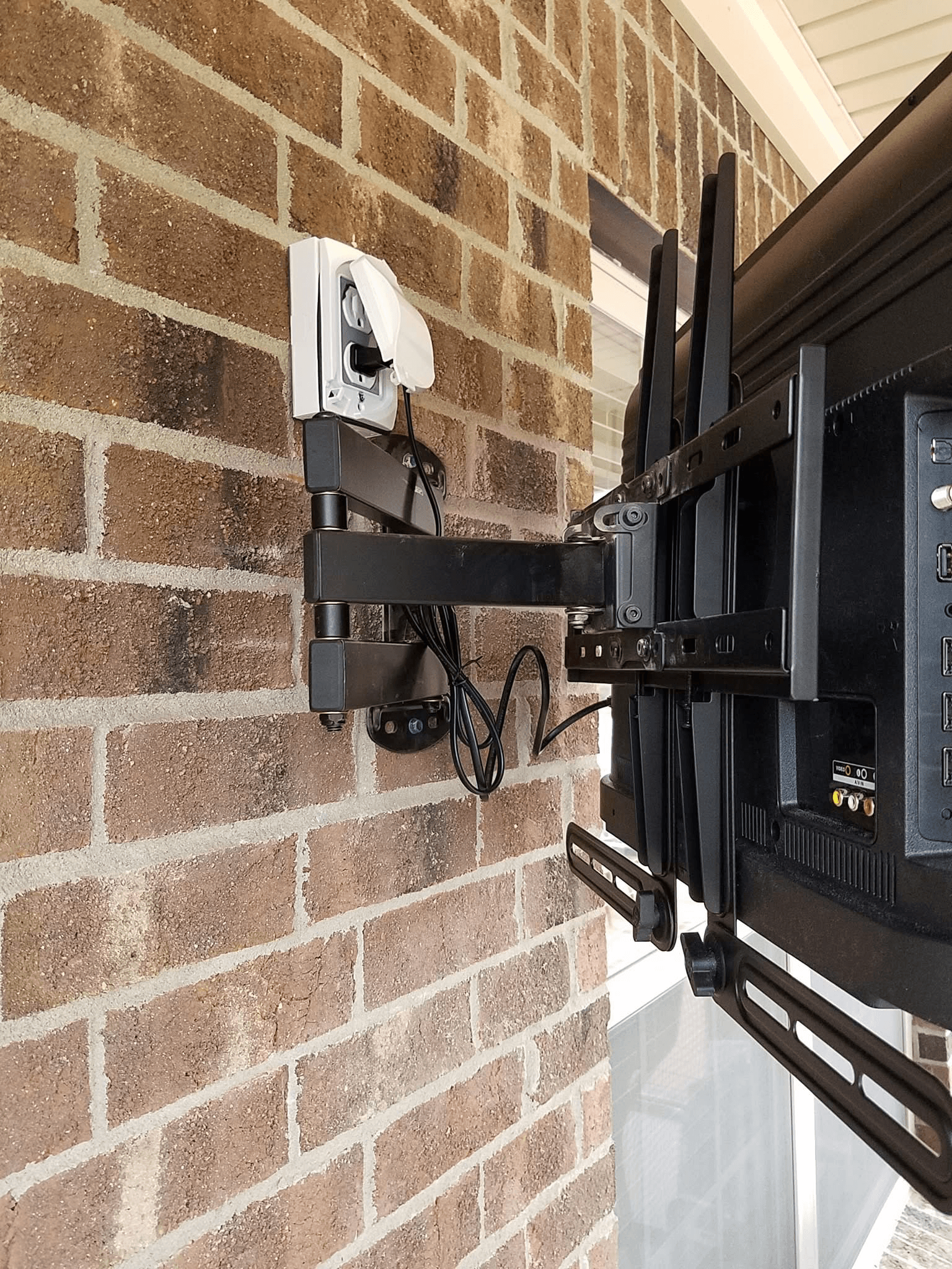 Full-motion mount hardware detail on outdoor brick wall