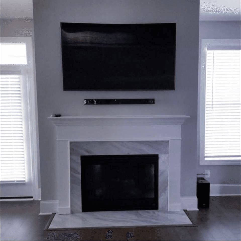 TV and soundbar mounted above gray fireplace with marble tile surround