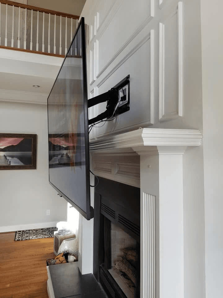 Full-motion TV mount extended from wall above fireplace mantle