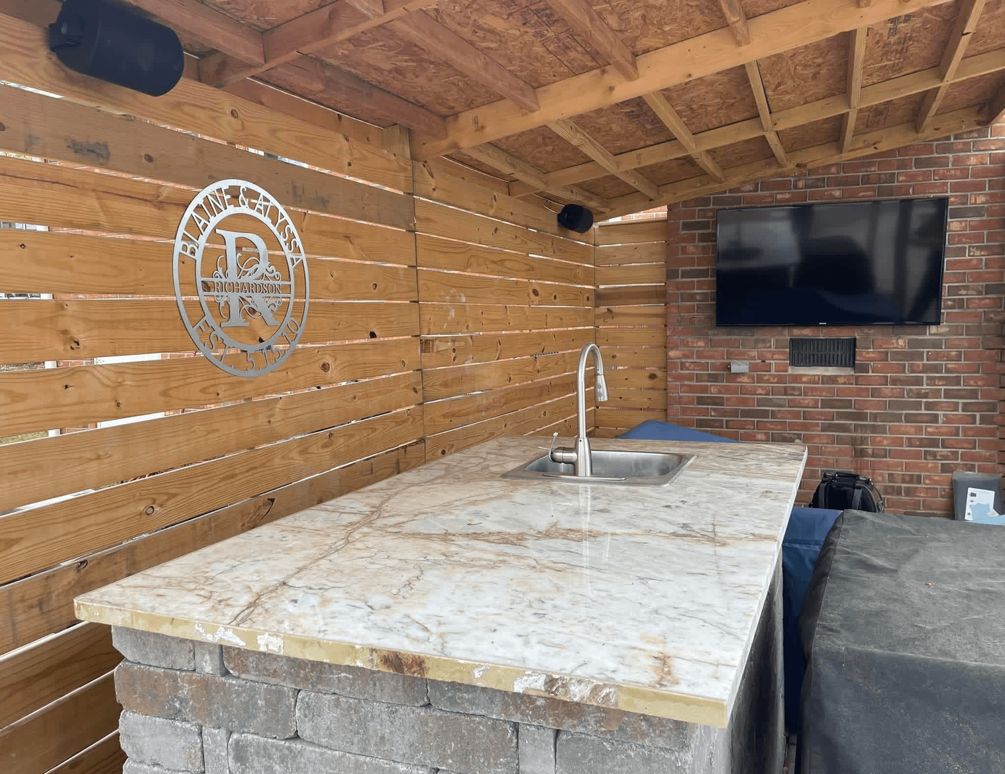 Outdoor covered patio with TV and Sonos outdoor speakers on brick wall